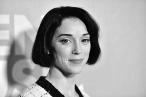 Annie Clark smiling wearing a white and black tweed top in this black and white photo.