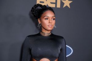 Janelle Monáe looking right wearing a black cutout dress and stacked black choker necklaces.