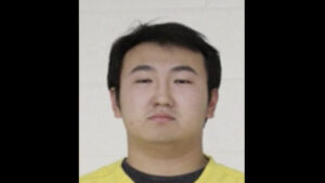 mugshot of Asian man in yellow shirt