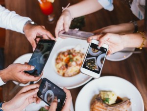 Group of friends going out and taking a photo of Italian food together with mobile phone, food trends, foodie concept.