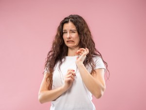 Young woman with disgusted expression repulsing something.