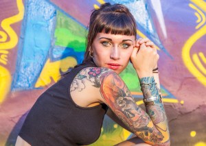 Tattooed rebel girl posing against a wall.