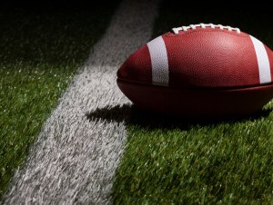 Low angle view of a college style football at a yard line with dramatic lighting, nfl concept