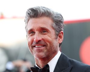 Patrick Dempsey attends a red carpet for the movie "Ferrari" at the 80th Venice International Film Festival smiling wearing a tux.