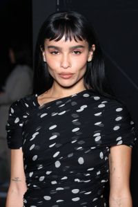 Zoë Kravitz attends the Saint Laurent Womenswear Spring/Summer 2024 show wearing a black polka dot shirt.