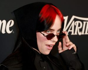 Billie Eilish attends the 2023 Variety Power Of Women facing right holding her sunglasses down.