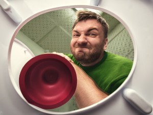 Man cleaning the toilet with cup plunger, clogged toiletconcept