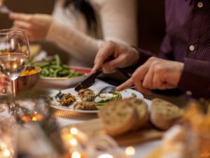 food, holidays and celebration concept - close up of man having christmas dinner and eating meat at home