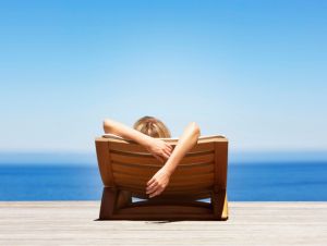 Rear view of woman reclining on folding chair outdoors, solo vacations concept.