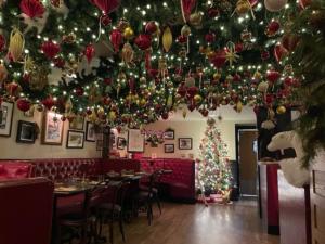 Interior view of restaurant fully decorated for Christmas. With ornaments on the ceiling and a lit tree.
