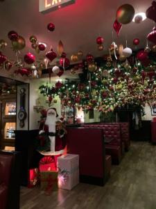 A Santa display and restaurant room decorated with presents, garland and ornaments.