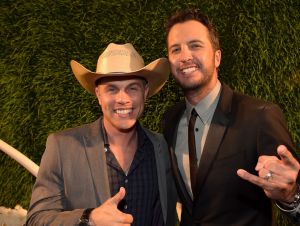 Dustin Lynch in a cowboy hat and gray blazer and Luke Bryan in a black suit