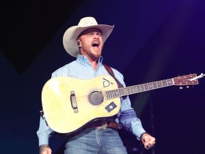 Cody Johnson on stage singing in a blue shirt and cowboy hat
