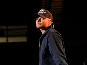 Kane Brown on stage wearing a black ball cap and black jacket