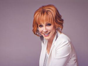 Reba McEntire in a white blazer and top posing