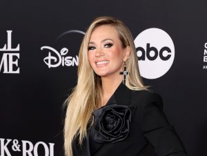 Carrie Underwood wearing a black jumpsuit and smiling