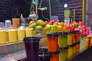 Multicolored fruit drink smoothies and juice in plastic cups stand on the counter.