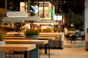 Background image of food court interior in shopping mall with wooden tables in row lit by warm light. The LineUp Boston opens on January 17
