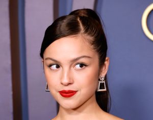 Olivia Rodrigo attends the Academy Of Motion Picture Arts & Sciences' 14th Annual Governors Awards smiling looking right wearing a sleeveless dress.