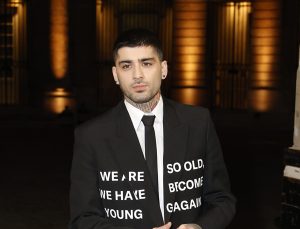 Zayn Malik attends the Valentino Menswear Fall/Winter 2024-2025 show as part of Paris Fashion Week wearing a black graphic blazer looking left.