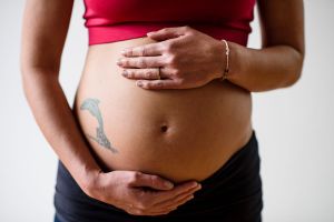 Pregnant woman holding stomach. How many women did one guy get pregnant at same time?