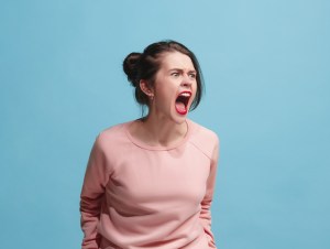 Screaming, hate, rage. Crying emotional angry woman screaming on blue studio background. Emotional, young face. Female half-length portrait. Human emotions, facial expression concept. Trendy colors