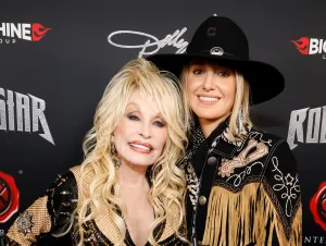 Dolly Parton wearing black with Lainey Wilson also wearing black with a cowboy hat.