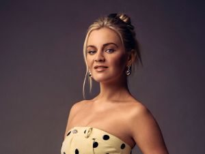 Kelsea Ballerini posing in a yellow polka-dot dress.