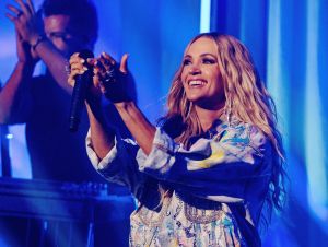 Carrie Underwood on stage in a denim jacket clapping