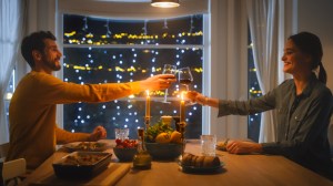 Happy Young Couple Have Romantic Dinner, Toasting Each other with Glasses of Wine, Eating Tasty Meal in the Kitchen, Celebrating,