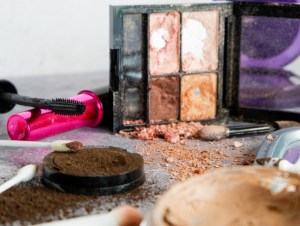 Old, dried-up eyeshadow, foundation, and mascara spilled out onto countertop, makeup concept.