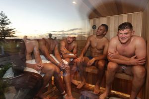 Men sitting in a sauna in towels.