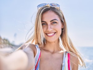 Young woman smiling happy make selfie by the smartphone at the beach.