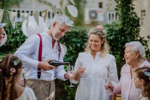 A mature bride and groom toasting with guests at wedding reception outside in the backyard.