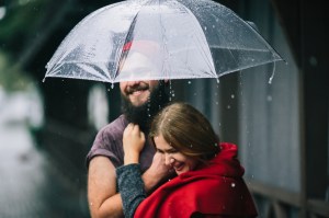 guy and the girl posing together in the rain on a city street