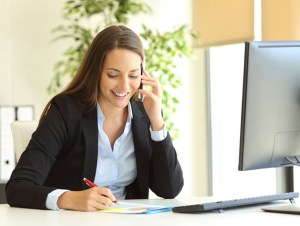 Executive assistant calling on phone and taking notes