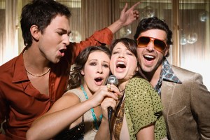 4 Friends doing karaoke singing into a microphone