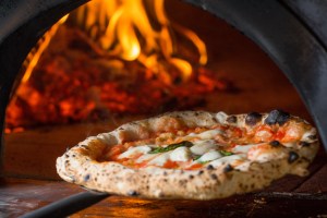 baked margarita pizza being taken out of the oven.