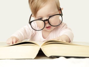 Adorable baby in front of big thick book, studio shot.