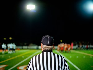 American football referee on field, rear view