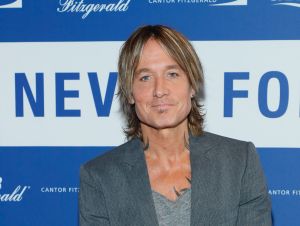 Keith Urban posing in a gray blazer and a gray shirt.