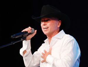 Kenny Chesney in a white shirt and black cowboy hat on stage.