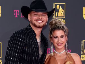 Kane Brown in a black suit and a cowboy hat with his wife Katleyn in an orange dress.