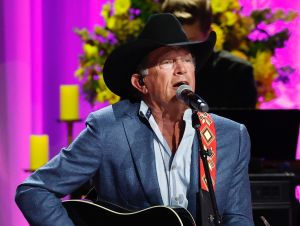 George Strait on stage performing in a black cowboy hat and blue blazer.