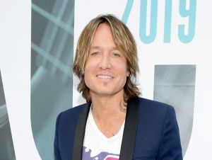 Keith Urban is wearing a white printed t-shirt and a blue blazer.