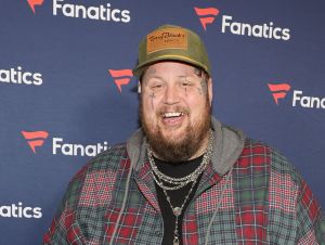 Jelly Roll's Father - Jelly Roll wearing a plaid shirt, tan hat, and smiling on a red carpet.