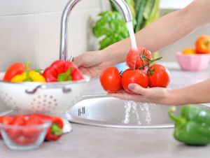 A person washing red vegetables.