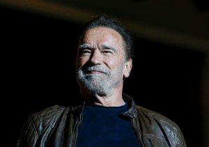 Arnold Schwarzenegger speaks during Netflix's Tudum: A Global Fan Event 2023 smiling looking left with a leather jacket, Arnold Schwarzenegger Has A Pacemaker After 3 Surgeries.