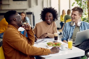 Students laughing at a dining hall enjoying college food on campus.