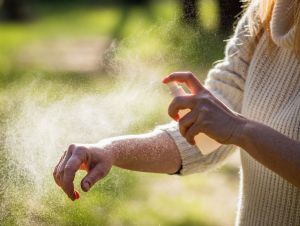 A woman spraying insect repellent.